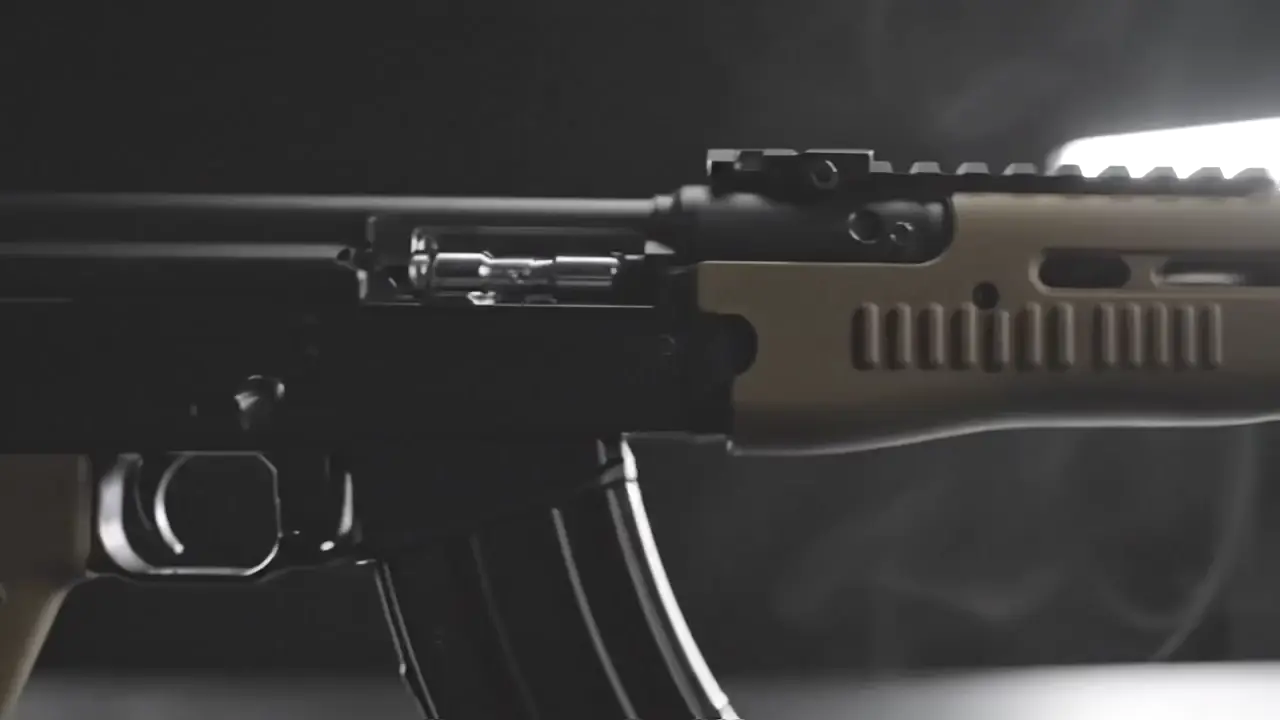 Rifle barrel and optic in deep, low-key tactical lighting